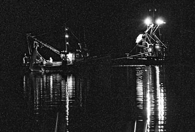 HAULING BACK a purse seine set for herring off Eastport are crew members on Earl Small’s Fundy Gem (left), as the carrier Jenny Rose tows on the seiner to keep it away from the net. The herr