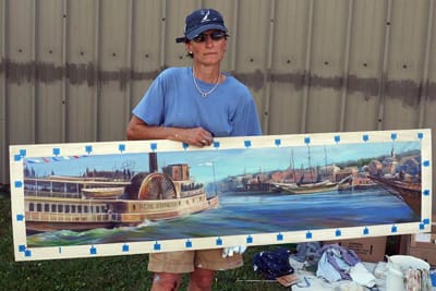 ARTIST AMY BARTLETT WRIGHT holds up her finalized concept image of the soon-to-be-completed mural on the side of the Calais Community Thrift Store. Bartlett Wright has been working since Aug