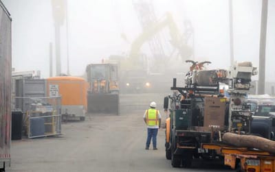 A FOGGY BALLET. Heavy construction equipment moves through the mist as CPM Constructors drives sheet piling and removes fill from the Eastport breakwater on an August morning. The reconstruc