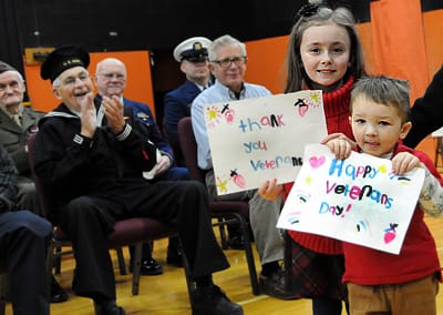 EXPRESSING THEIR GRATITUDE to veterans with their handmade signs are Ivory Flood, 8, and her brother Tannar, 3, at the Veterans Day ceremony in Eastport on November 11. See this issue for co