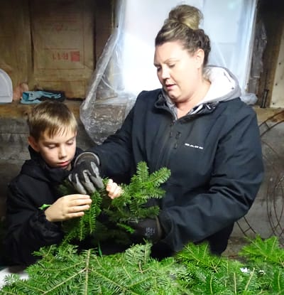 THIRD GENERATION WREATH-MAKER Savannah McPherson teaches her son, Lucas Scoville, the art of sculpting holiday greenery. “We tip our own brush and craft Christmas wreaths, centerpieces, swag