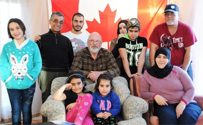 RELIEVED TO NOW BE IN CANADA, the Maatouk family poses in front of the Canadian flag in their new home in St. Stephen. In front, left to right, are: daughter Cherine, 9, daughter Hanon, 4, a