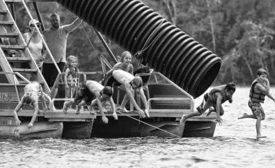COOLING OFF ON A HOT DAY. Jumping in for a swim off Jeff Turner’s pontoon boat at Boyden’s Lake are some happy kids. Built in 2008 by Jason Brown, Bush Kerby and Tommy Critchley, it can be a