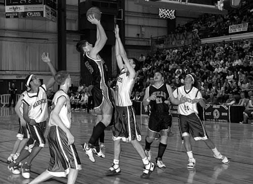 DANA MITCHELL of Shead takes a shot over a Deer Isle-Stonington player during a quarter final contest in the Bangor Auditorium. Shead lost, but the Tigers completed their best season in rece