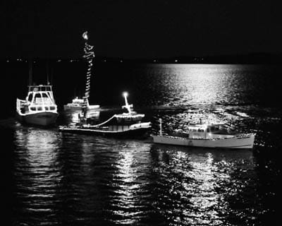 DECORATED VESSELS of all sizes show off in front of the Eastport breakwater under a moonlit sky during the annual Eastport Boat Parade on December 11. (Don Dunbar photo)