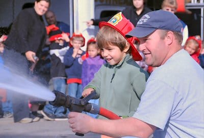 A FUTURE FIREFIGHTER? Firefighter Tom Critchley and kindergartner Jesse Calame try out spraying water with a fire hose during a visit to the Timothy P. Mullen Central Fire Station by Eastpor