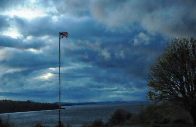 AGAINST A BACKDROP OF STORM CLOUDS over Western Passage, the U.S. flag still flies above the graves of those now at rest at Bayside cemetery in Eastport. (Edward French photo)