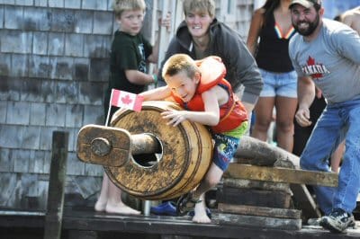 Noah Leonard attempts to capture the flag at the end of the greasy pole during the Canada Day celebration on July 2 at Seal Cove creek on Grand Manan Island. ( Jennifer Pierce photo)
