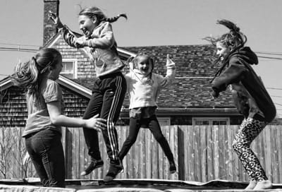 SPRINGING JOYFULLY in anticipation of summer, Ella Lewey, Jay-Len Follis, Lily Sault and Kelsey Sault enjoy playing outside in Eastport on one of the first warm days of spring. (Edward Frenc