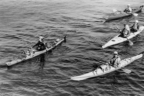 ESCORTED BY A FLOTILLA of welcoming kayakers as she approaches land in Eastport is adventurer Renata Chlumska of Sweden (far left). Chlumska is aiming to be the first person to circumnavigat