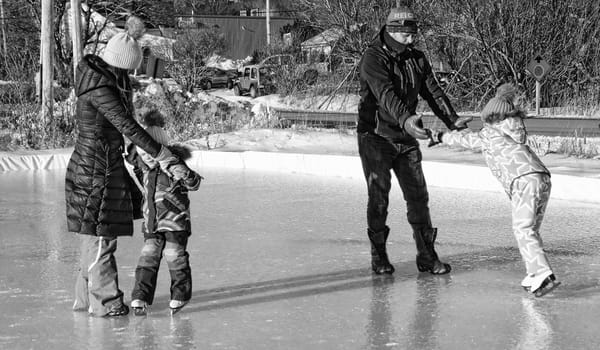 LEARNING HOW TO SKATE are sisters Eleanor and Natalie, assisted by their parents, Chris and Vicki Mello, at the skating rink next to the Eastport Youth Center. The Rhode Island family was vi