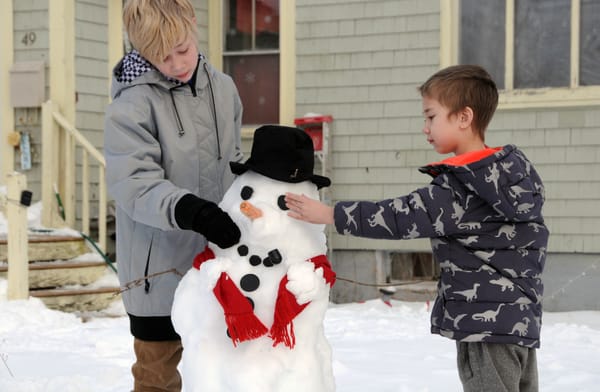 PLACING THE FINISHING TOUCHES on their snowman, which they made outside their Eastport home after the January 23 snowstorm, are brothers Vinny and Xander Eisworth. (Edward French photo)