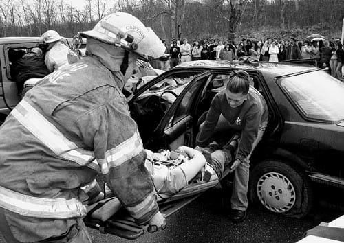 TAKING PART IN A MOCK ACCIDENT, Captain Teddy Morse of the East Machias Fire Department and Vanessa Reed remove a Washington Academy student from a fatal automobile re-enactment. Wakeup Call