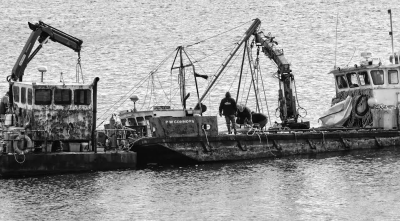 RAISING THE MISS TESS, a 34-foot fishing boat owned by Justin McPhail of Perry, are two barges from Cooke Aquaculture. Also helping out to raise the boat was diver Scott MacNichol, and McPha