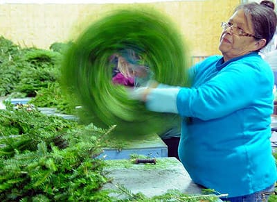 THE WREATH-MAKING SEASON brings work for many in Downeast Maine. Twirling a wreath to make sure all of the tips are firmly in place is Annette Newell at the Quoddy Village shop run by Mingo'