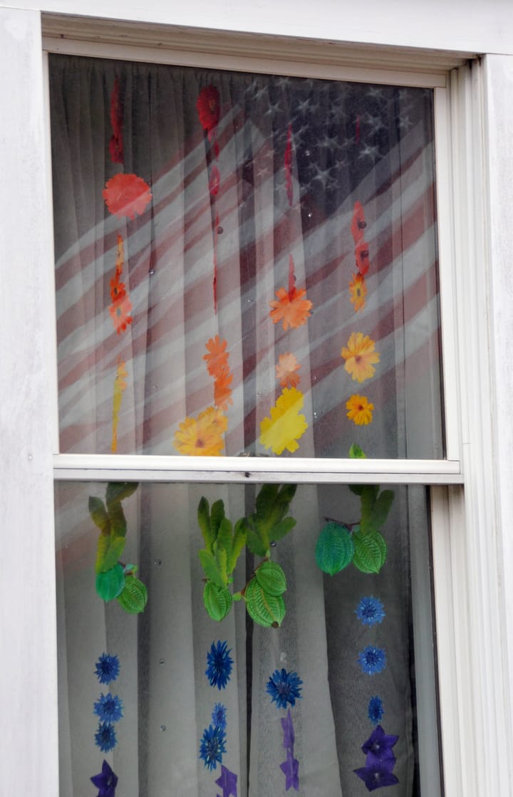 REFLECTIONS ON THE FOURTH. An American flag is reflected in this Eastport window that is decorated with flowers. (Edward French photo)