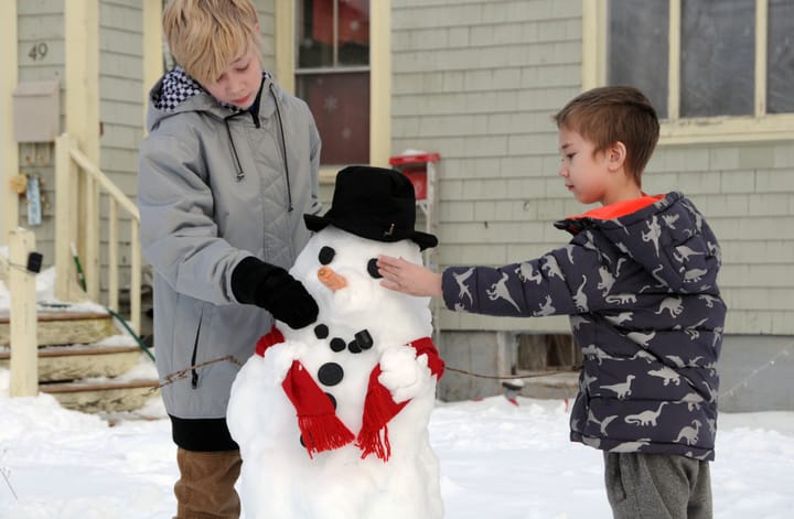 PLACING THE FINISHING TOUCHES on their snowman, which they made outside their Eastport home after the January 23 snowstorm, are brothers Vinny and Xander Eisworth. (Edward French photo)