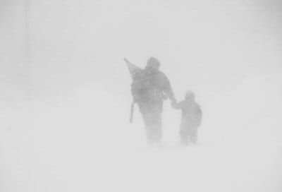 HEADING INTO A WHITEOUT, Heron Weston holds the hand of his four-year-old son Kieran as they walk out Clark Street in Eastport during the February 2 snowstorm. Over a foot of snow fell on th